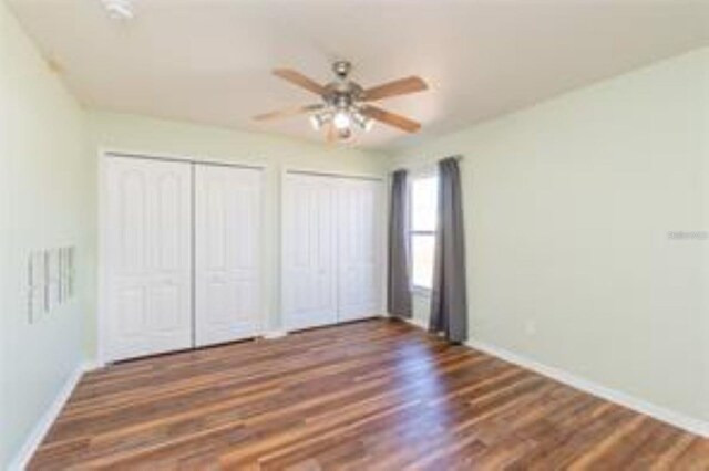 10247 Mason Loop, Clermont, FL 34711 - unfurnished bedroom with multiple closets, baseboards, wood finished floors, and ceiling fan