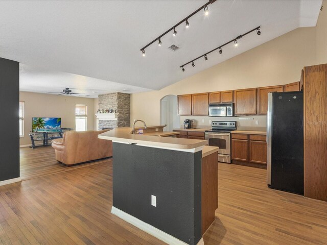 10247 Mason Loop, Clermont, FL 34711 - kitchen with appliances with stainless steel finishes, brown cabinets, ceiling fan, arched walkways, and a fireplace