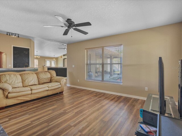10247 Mason Loop, Clermont, FL 34711 - living room with a ceiling fan, rail lighting, a textured ceiling, wood finished floors, and baseboards