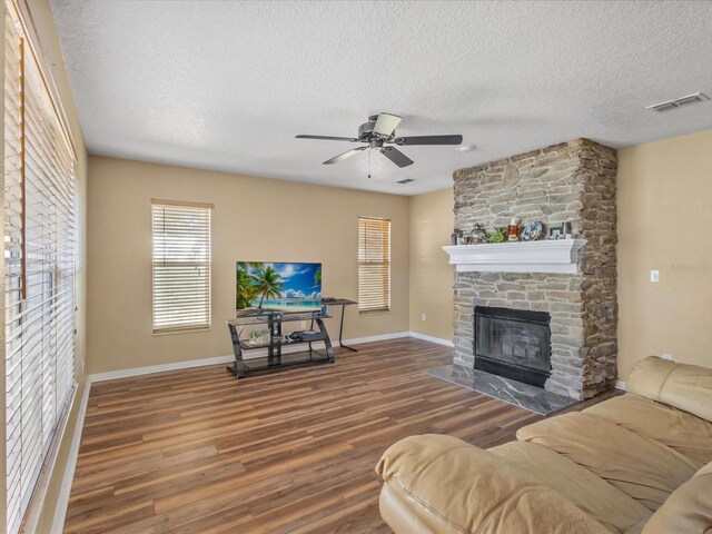10247 Mason Loop, Clermont, FL 34711 - living room with wood finished floors, a textured ceiling, a stone fireplace, baseboards, and ceiling fan