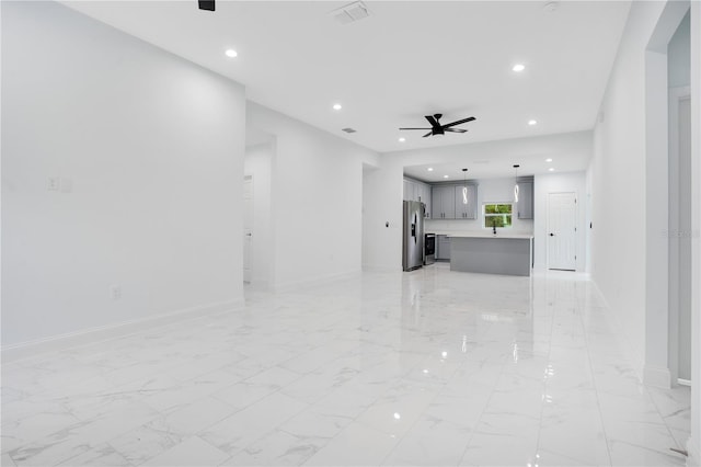 unfurnished living room featuring ceiling fan, recessed lighting, light marble finish flooring, and baseboards