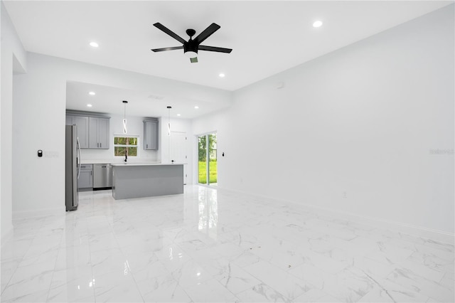 unfurnished living room with ceiling fan, recessed lighting, baseboards, a sink, and light marble finish flooring