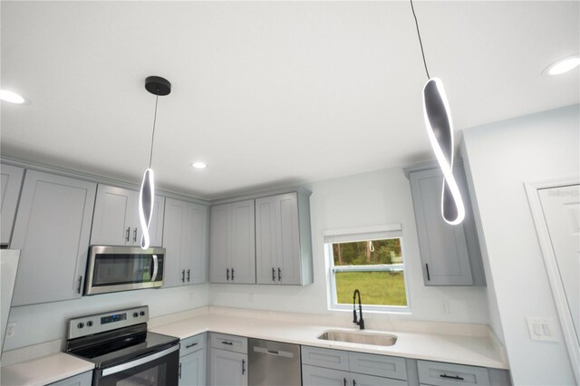 kitchen with appliances with stainless steel finishes, a sink, gray cabinets, light countertops, and recessed lighting