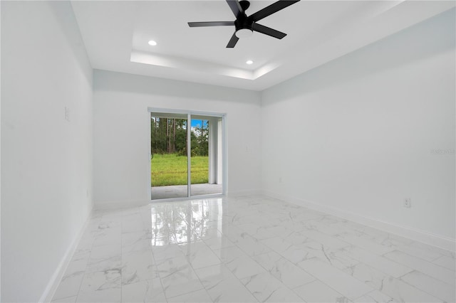 unfurnished room featuring baseboards, a tray ceiling, light marble finish floors, recessed lighting, and a ceiling fan