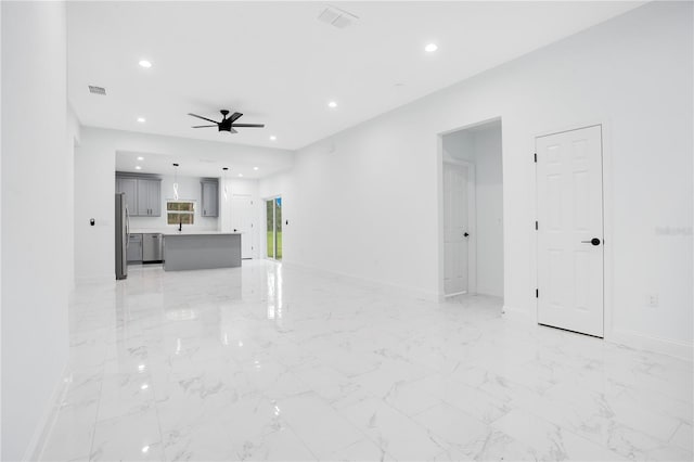 unfurnished living room featuring a ceiling fan, recessed lighting, baseboards, and light marble finish floors