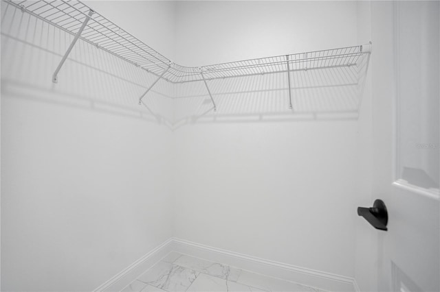 walk in closet with light marble finish flooring