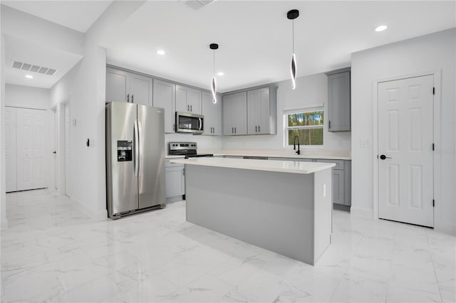 kitchen featuring appliances with stainless steel finishes, gray cabinetry, a sink, light countertops, and a center island