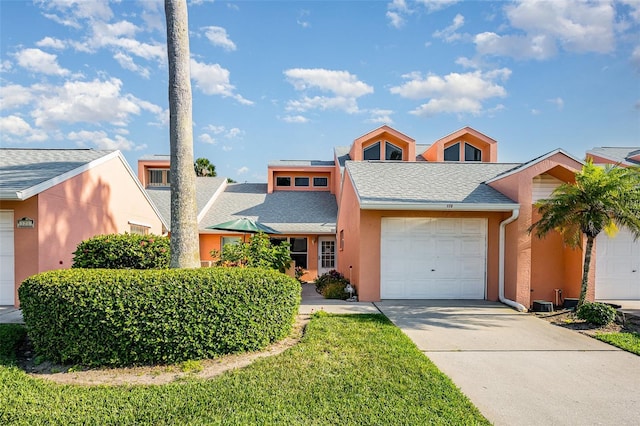 view of front of home with a garage, driveway, a shingled roof, and stucco siding