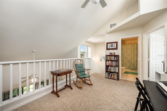 sitting room with ceiling fan, carpet flooring, and vaulted ceiling