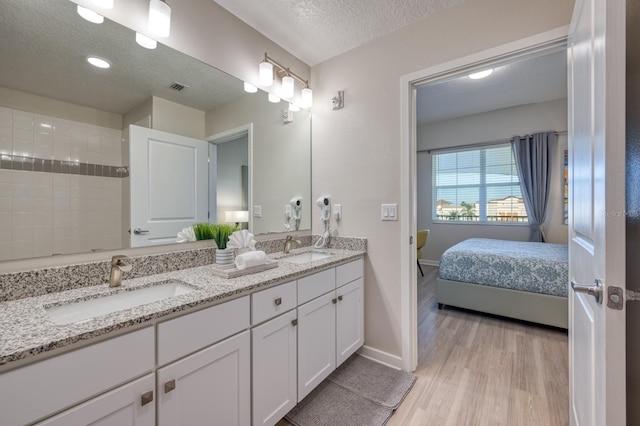4013 Breakview Dr Unit A407, Orlando, FL 32819 - ensuite bathroom with a textured ceiling, wood finished floors, baseboards, and double vanity