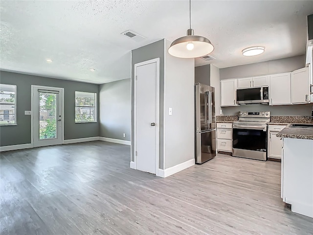 8228 Shriver Dr, Orlando, FL 32822 - kitchen featuring stainless steel appliances, light wood finished floors, dark countertops, baseboards, and a textured ceiling