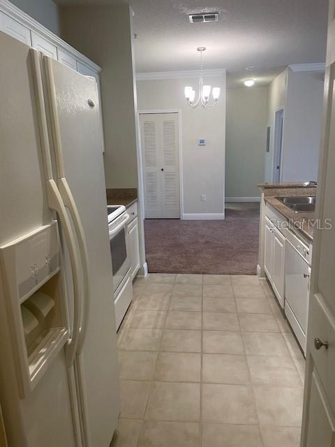 417 Southern Pecan Cir Unit 201, Winter Garden, FL 34787 - kitchen featuring white appliances, a sink, crown molding, a chandelier, and light colored carpet