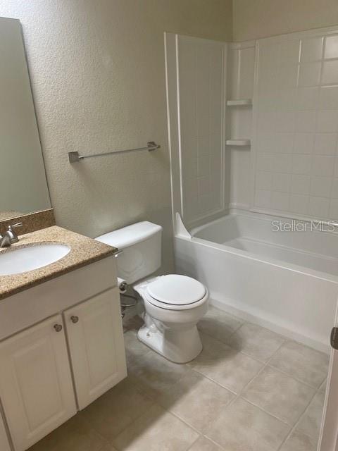 417 Southern Pecan Cir Unit 201, Winter Garden, FL 34787 - bathroom with toilet, a textured wall, vanity, tile patterned flooring, and shower / tub combination