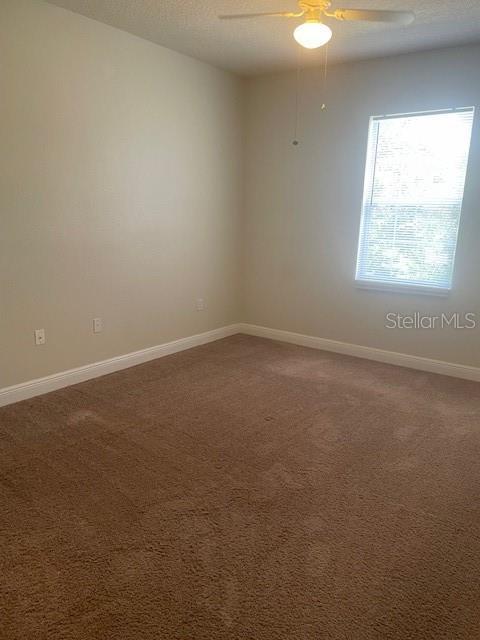 417 Southern Pecan Cir Unit 201, Winter Garden, FL 34787 - empty room with dark carpet, a ceiling fan, and baseboards