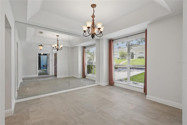 unfurnished dining area with a chandelier, a tray ceiling, and baseboards