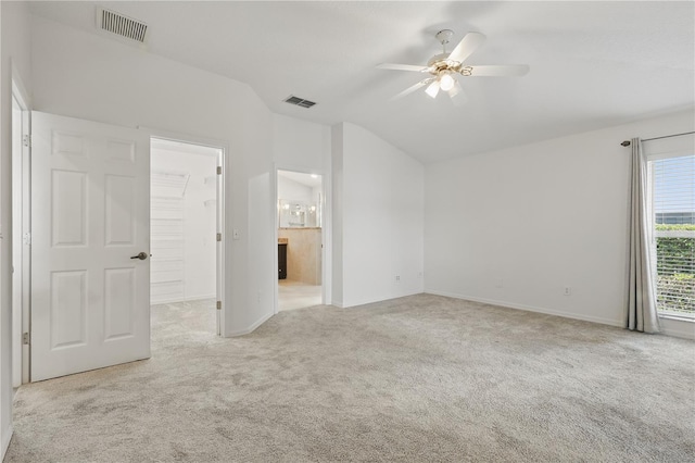 unfurnished bedroom featuring vaulted ceiling, carpet flooring, baseboards, ensuite bathroom, and a ceiling fan