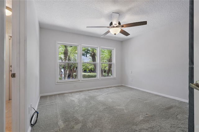 carpeted spare room featuring ceiling fan, a textured ceiling, and baseboards