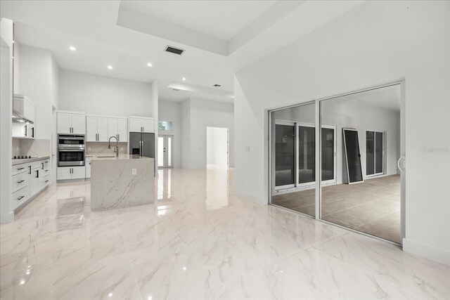 4528 Yorkshire Ln, Kissimmee, FL 34758 - kitchen with a sink, a towering ceiling, a center island with sink, white cabinets, and appliances with stainless steel finishes