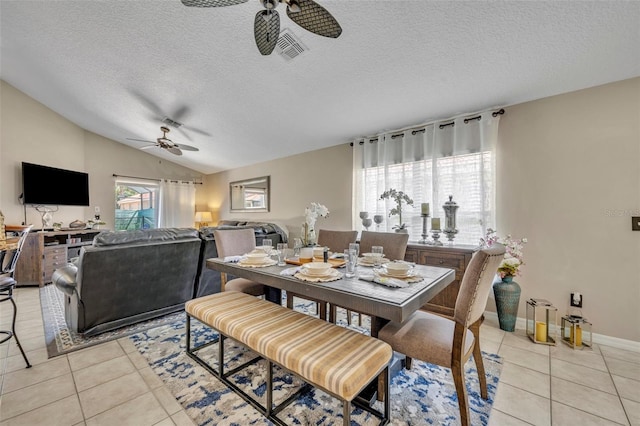 dining room with ceiling fan, light tile patterned floors, vaulted ceiling, a textured ceiling, and baseboards