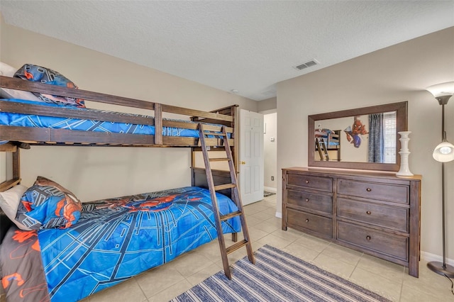bedroom featuring light tile patterned floors, a textured ceiling, and baseboards