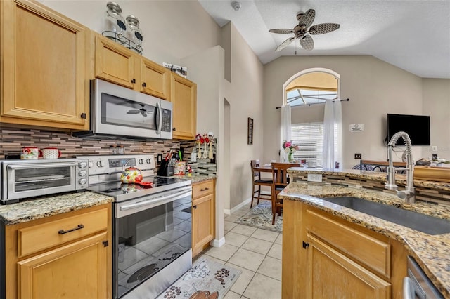 kitchen featuring appliances with stainless steel finishes, a sink, a ceiling fan, tasteful backsplash, and light tile patterned flooring