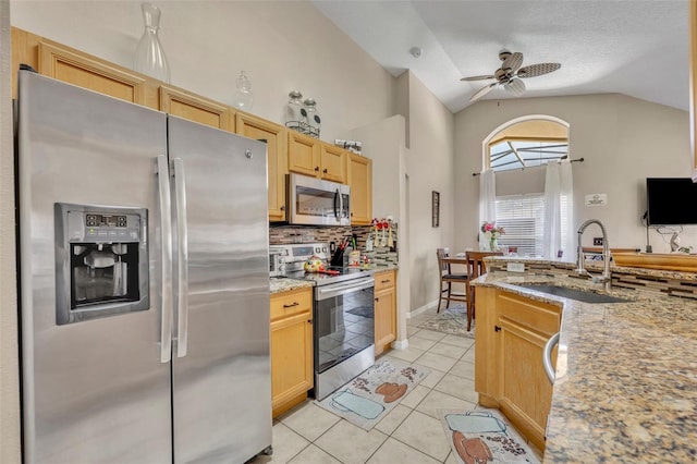 kitchen featuring stainless steel appliances, a sink, lofted ceiling, backsplash, and light tile patterned floors
