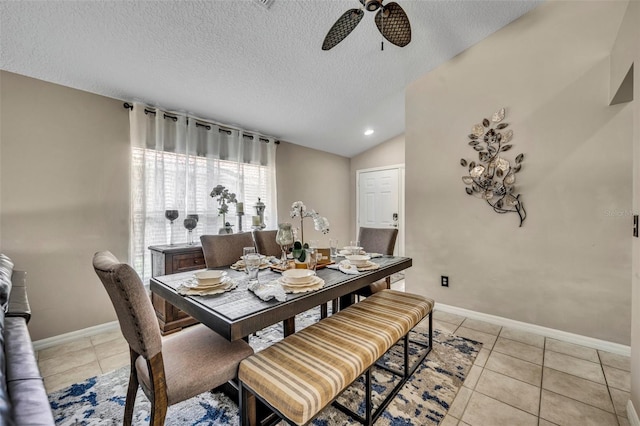 dining room with a ceiling fan, baseboards, light tile patterned floors, a textured ceiling, and lofted ceiling