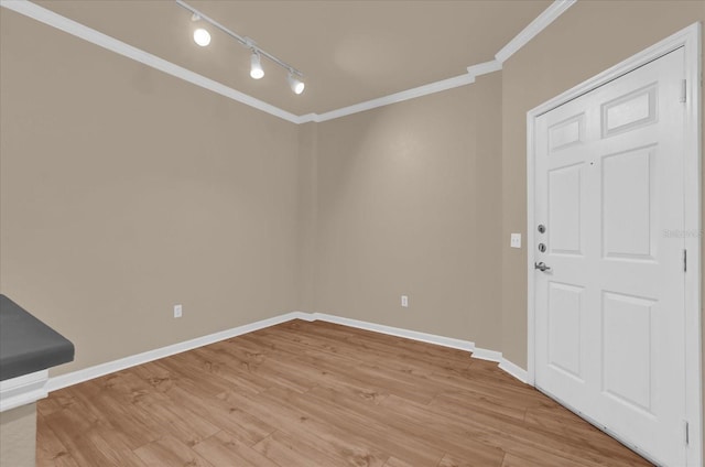 unfurnished room with rail lighting, ornamental molding, light wood-style floors, and baseboards