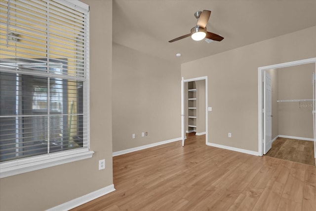 spare room featuring ceiling fan, light wood-type flooring, and baseboards