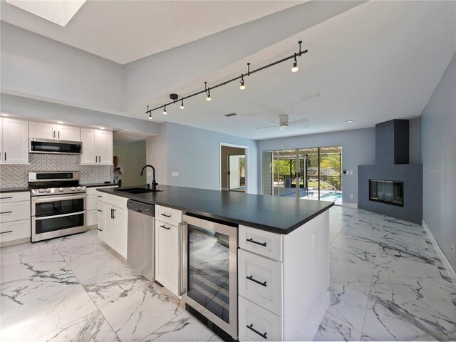208 Frinton Cv, Longwood, FL 32779 - kitchen featuring stainless steel appliances, wine cooler, a sink, dark countertops, and light marble finish flooring