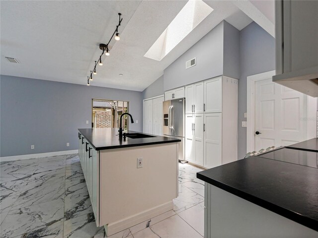 208 Frinton Cv, Longwood, FL 32779 - kitchen featuring stainless steel fridge, a skylight, light marble finish floors, dark countertops, and lofted ceiling