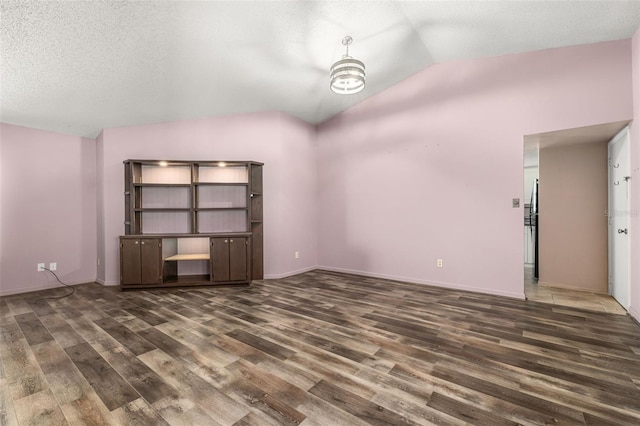 11811 Scarecrow Ln, Orlando, FL 32821 - empty room with wood finished floors, lofted ceiling, and a textured ceiling