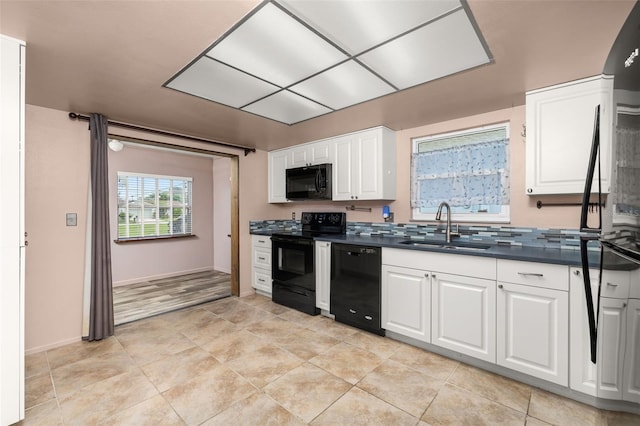 11811 Scarecrow Ln, Orlando, FL 32821 - kitchen featuring black appliances, a sink, dark countertops, white cabinets, and baseboards