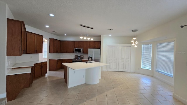 12126 Diedra Ct, Orlando, FL 32825 - kitchen with appliances with stainless steel finishes, a sink, an island with sink, light tile patterned floors, and light countertops