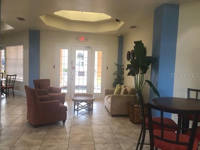 living room featuring light tile patterned floors, a raised ceiling, and baseboards