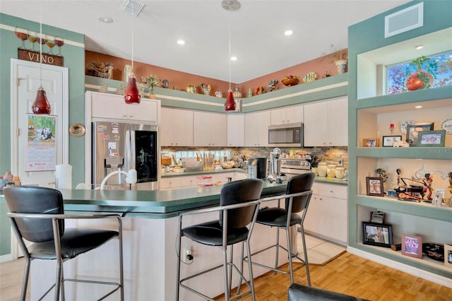 14680 Linden Dr, Spring Hill, FL 34609 - kitchen featuring appliances with stainless steel finishes, a kitchen breakfast bar, backsplash, a kitchen island, and white cabinetry