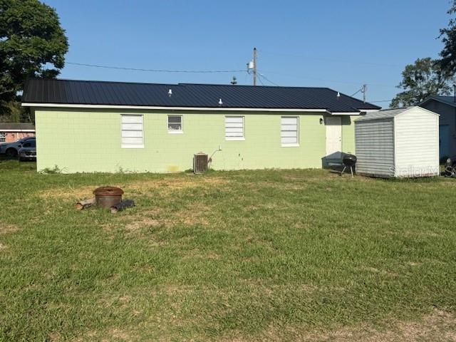 rear view of house featuring a storage unit, a yard, an outdoor structure, and central air condition unit