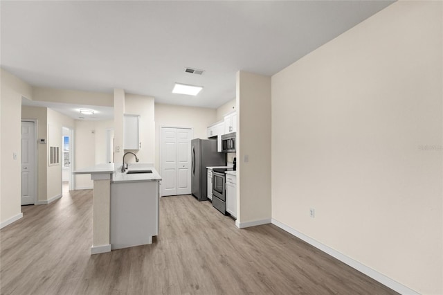 5447 Vineland Rd Unit 1308, Orlando, FL 32811 - kitchen with stainless steel appliances, light wood-type flooring, white cabinets, and a peninsula