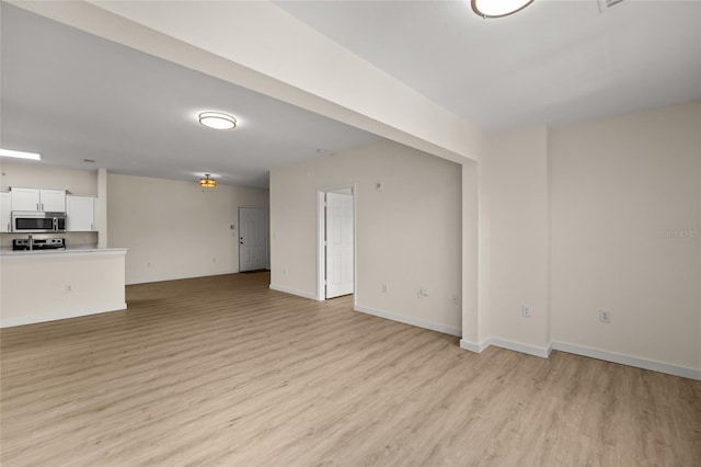 5447 Vineland Rd Unit 1308, Orlando, FL 32811 - unfurnished living room with light wood-style floors and baseboards