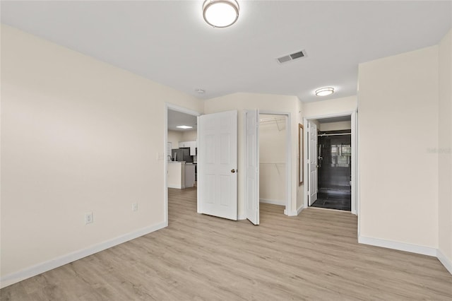 5447 Vineland Rd Unit 1308, Orlando, FL 32811 - unfurnished bedroom featuring light wood finished floors, baseboards, a closet, and stainless steel fridge with ice dispenser