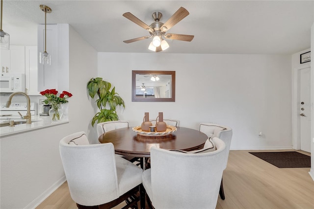 dining space featuring light wood-style flooring, baseboards, and ceiling fan
