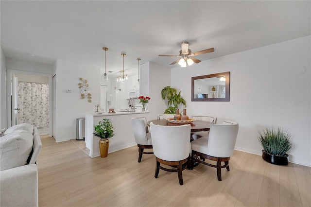 dining space with light wood-type flooring, ceiling fan, and baseboards