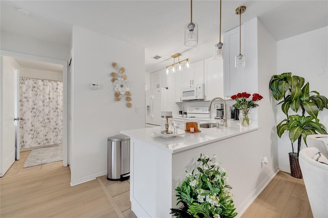 kitchen featuring white appliances, a sink, light wood finished floors, light countertops, and white cabinets