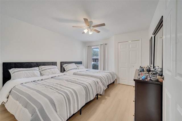 bedroom featuring light wood finished floors, ceiling fan, and a closet