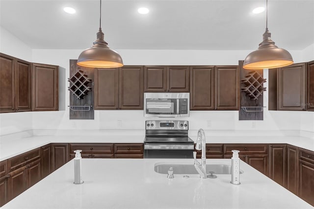 1050 20th St, Orlando, FL 32805 - kitchen featuring appliances with stainless steel finishes, light countertops, a sink, dark brown cabinets, and hanging light fixtures