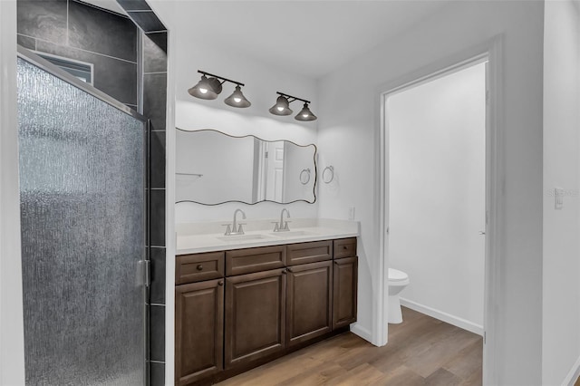 1050 20th St, Orlando, FL 32805 - full bathroom featuring double vanity, a stall shower, wood finished floors, toilet, and baseboards