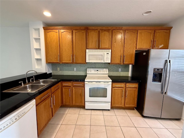 kitchen with white appliances, a sink, brown cabinetry, dark countertops, and recessed lighting