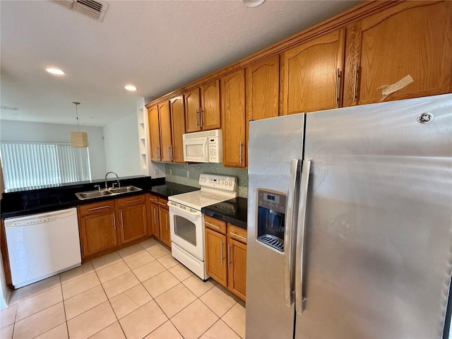 kitchen featuring white appliances, a sink, brown cabinets, light tile patterned floors, and recessed lighting