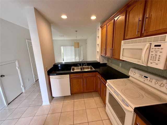 kitchen with white appliances, a sink, brown cabinets, dark countertops, and light tile patterned floors