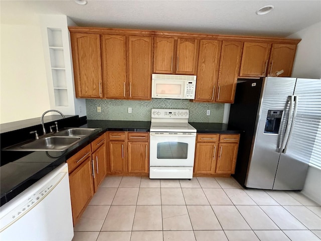 kitchen featuring white appliances, a sink, and brown cabinetry